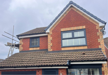 Front view of modern red brick home with black UPVC fascia and newly fitted windows