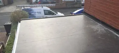 Flat roof with a sloped edge, viewed from above, and a delivery van parked on the street below.