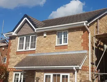 Two-story brick house with a gabled roof, featuring multiple windows and scaffolding on the right side.