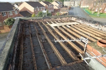 Roof with exposed wooden beams and metal framework, overlooking residential area and street.