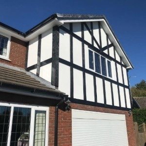 Tudor-style house exterior featuring black timber beams against white walls and a brick lower section.