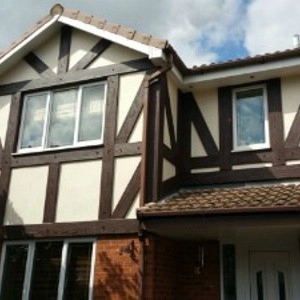 Tudor-style house with white and dark brown timber framing and multiple windows.