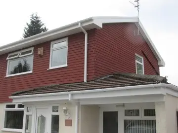 Two-story red house with white trim, visible windows, and a sloped roof.